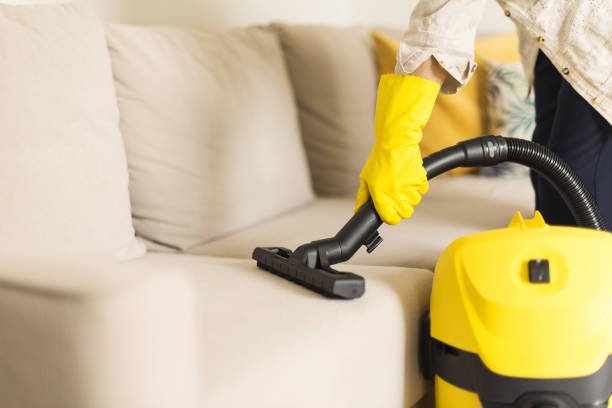 woman cleaning sofa with yellow vacuum cleaner. copy space. clean concept.