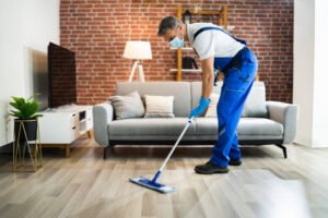 man cleaning the hardwood floor with mop in face mask
