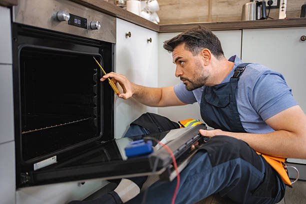 electrician repairing an electric oven using a screwdriver
